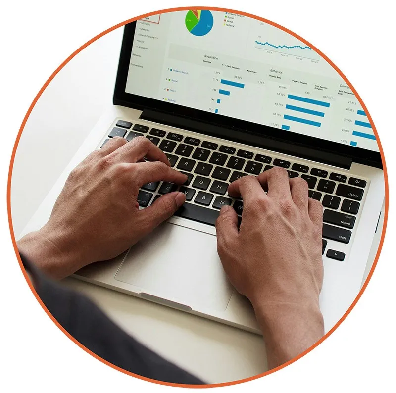 Hands typing on a silver laptop displaying colorful graphs and charts, suggesting data analysis or business work. The mood is focused and professional.